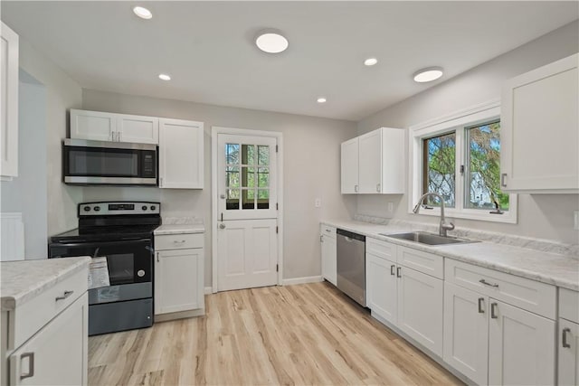 kitchen featuring white cabinets, appliances with stainless steel finishes, a wealth of natural light, and a sink