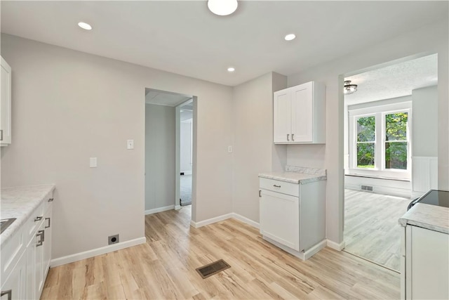 kitchen featuring light wood-style floors, baseboards, white cabinets, and visible vents