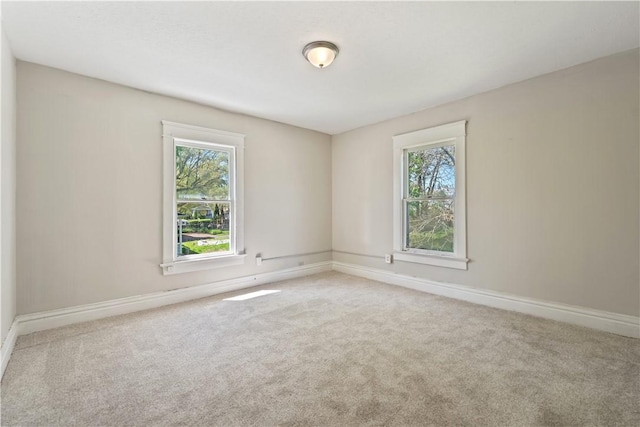 carpeted spare room featuring baseboards and a healthy amount of sunlight