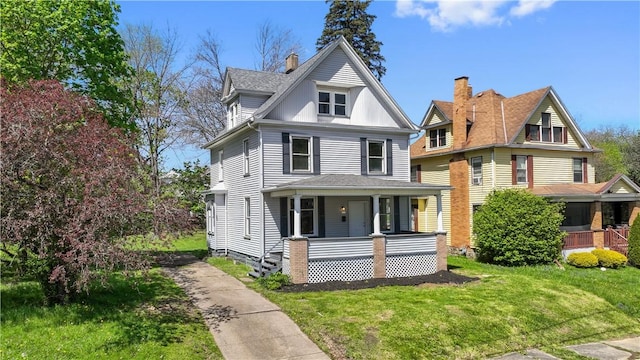 view of front facade featuring a shingled roof, covered porch, and a front yard