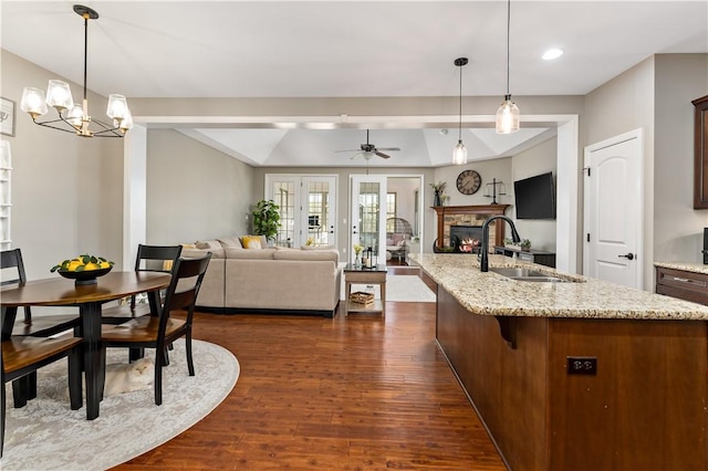 3061 Edelweiss Ct, Adams Twp, PA 16046 - kitchen with light stone counters, a sink, a fireplace, open floor plan, and dark wood-style floors