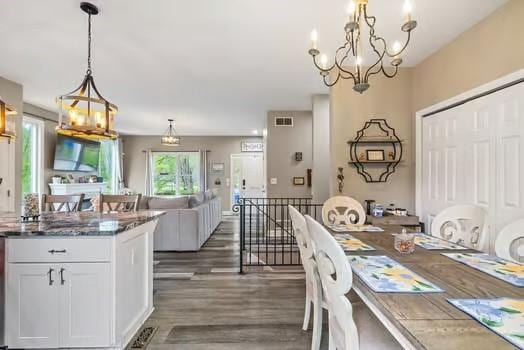 dining space featuring visible vents, dark wood-type flooring, and a notable chandelier