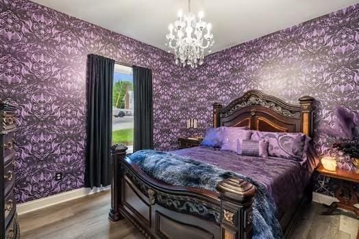 bedroom with baseboards, wood finished floors, a notable chandelier, and wallpapered walls
