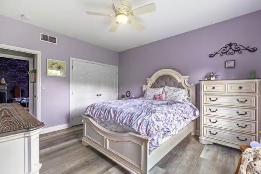 bedroom with baseboards, a closet, wood finished floors, and visible vents