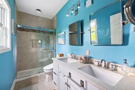 full bathroom featuring a sink, tile patterned floors, toilet, and a shower stall