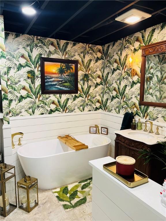 bathroom with vanity, a freestanding bath, a wainscoted wall, and wallpapered walls