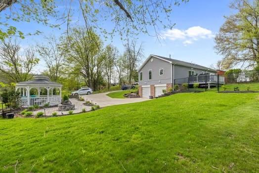 view of yard featuring concrete driveway, a gazebo, a wooden deck, and a garage