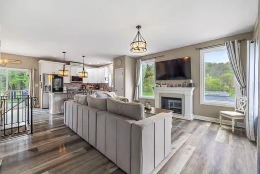 living area with plenty of natural light, a glass covered fireplace, wood finished floors, and a notable chandelier