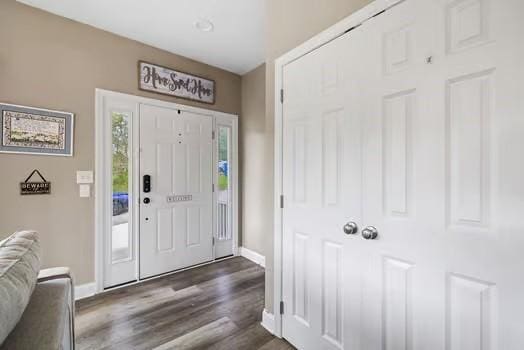 foyer featuring baseboards and dark wood-style floors