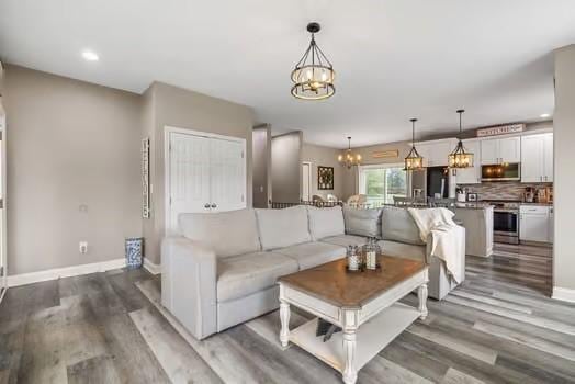living area featuring recessed lighting, baseboards, an inviting chandelier, and wood finished floors