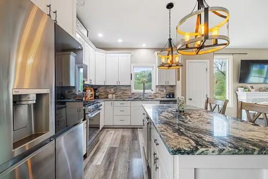 kitchen featuring plenty of natural light, a sink, appliances with stainless steel finishes, and an inviting chandelier