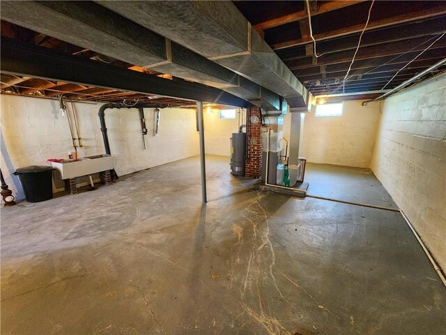 below grade area with a sink, heating unit, and gas water heater