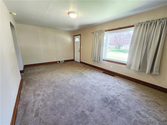 carpeted empty room featuring baseboards and visible vents