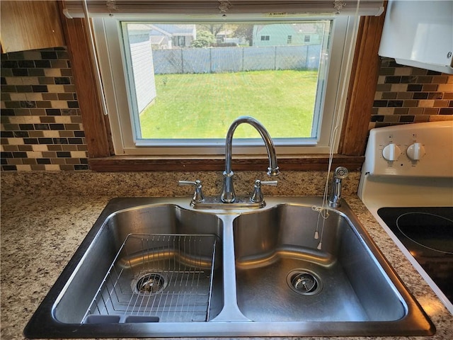 interior details featuring a sink, decorative backsplash, exhaust hood, and electric stove