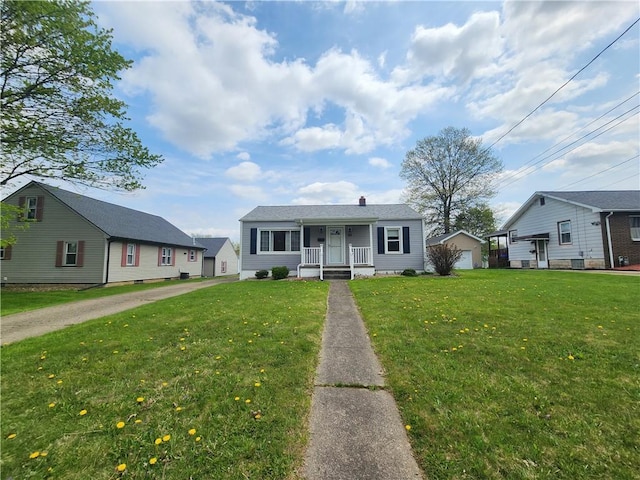 bungalow-style house with a porch, a chimney, an outbuilding, and a front yard