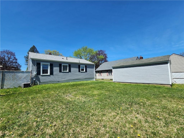 rear view of property featuring a lawn and fence