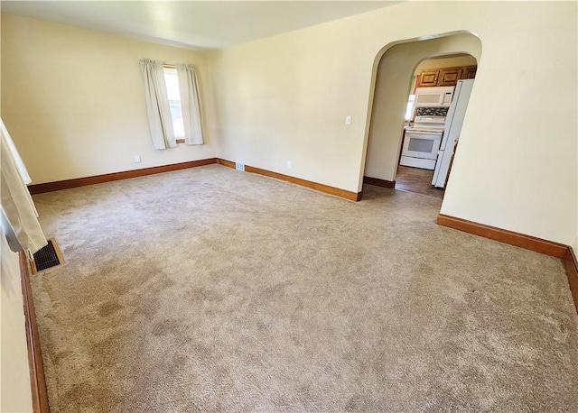 unfurnished room with arched walkways, baseboards, and visible vents