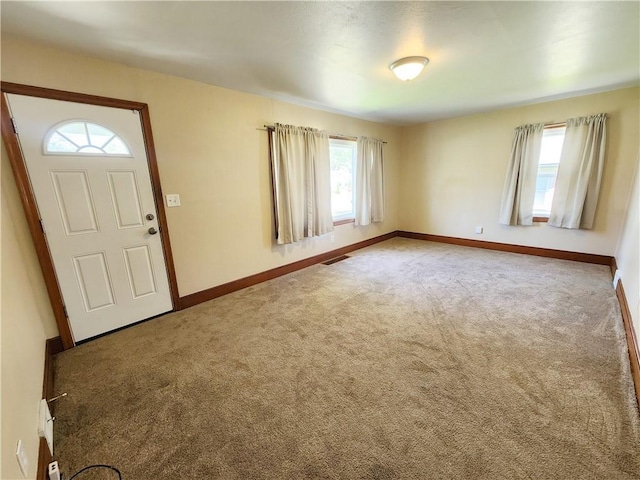 foyer with carpet floors, baseboards, and visible vents
