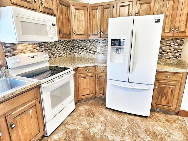 kitchen featuring brown cabinets, light stone countertops, a sink, white appliances, and tasteful backsplash