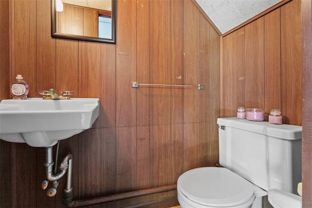 half bathroom featuring wood walls and toilet