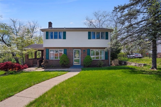 colonial home with fence, a chimney, brick siding, and a front yard