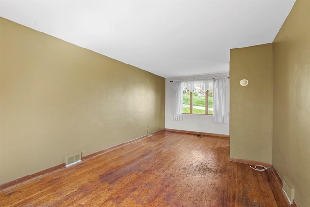 unfurnished room with visible vents, baseboards, and wood finished floors