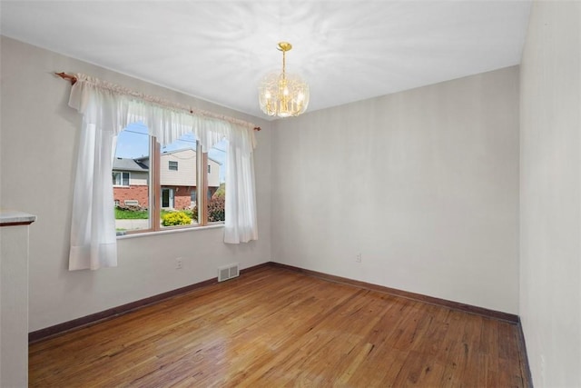 unfurnished room featuring baseboards, visible vents, light wood-style flooring, and a chandelier