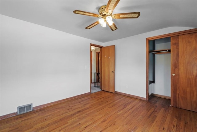 unfurnished bedroom with visible vents, a closet, wood finished floors, baseboards, and ceiling fan