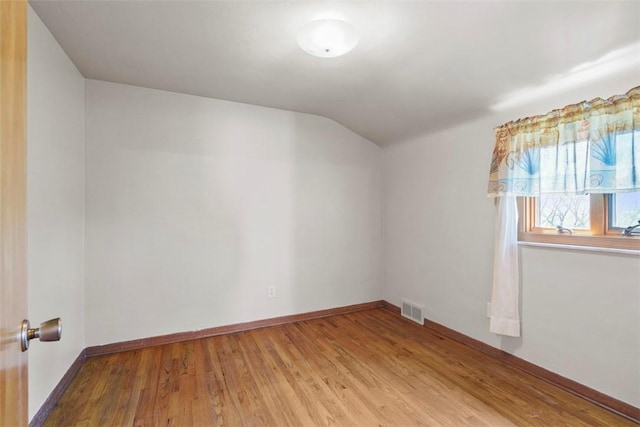 bonus room with baseboards, lofted ceiling, light wood finished floors, and visible vents