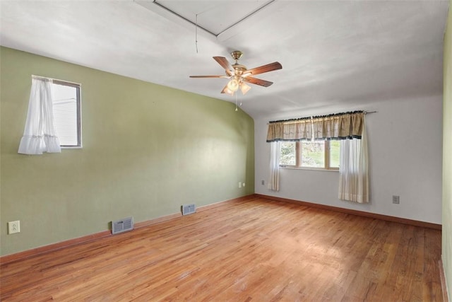 unfurnished room featuring baseboards, attic access, wood finished floors, and visible vents