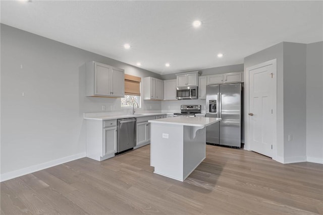 kitchen featuring baseboards, light countertops, light wood-style flooring, and appliances with stainless steel finishes