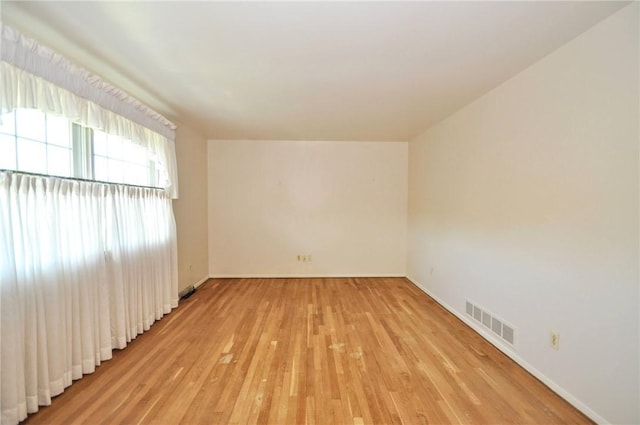 unfurnished room with baseboards, visible vents, and light wood-style flooring