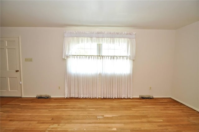 unfurnished room with baseboards and light wood-type flooring