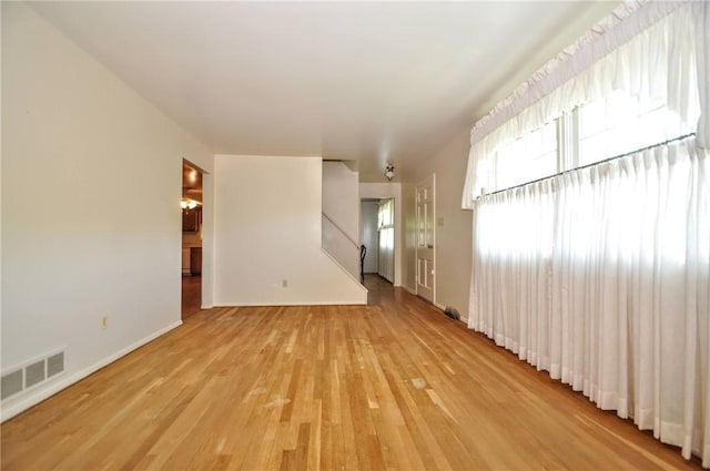 spare room featuring stairs, baseboards, visible vents, and light wood-style flooring