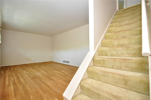 staircase featuring baseboards, visible vents, and hardwood / wood-style flooring