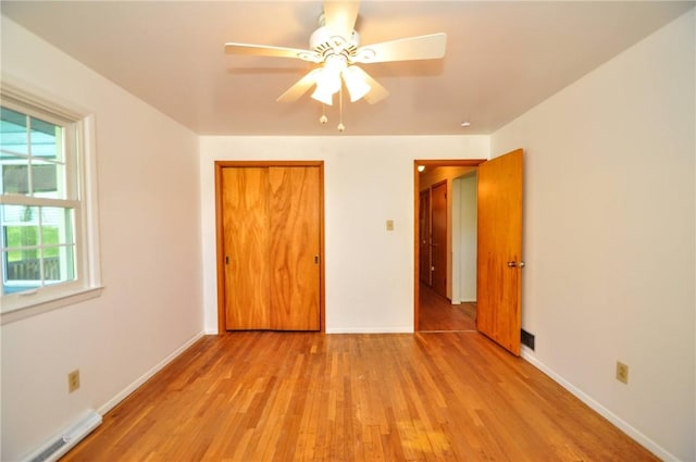 unfurnished bedroom with baseboards, a baseboard heating unit, light wood-style flooring, and a closet