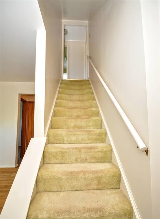 stairway with baseboards and wood finished floors