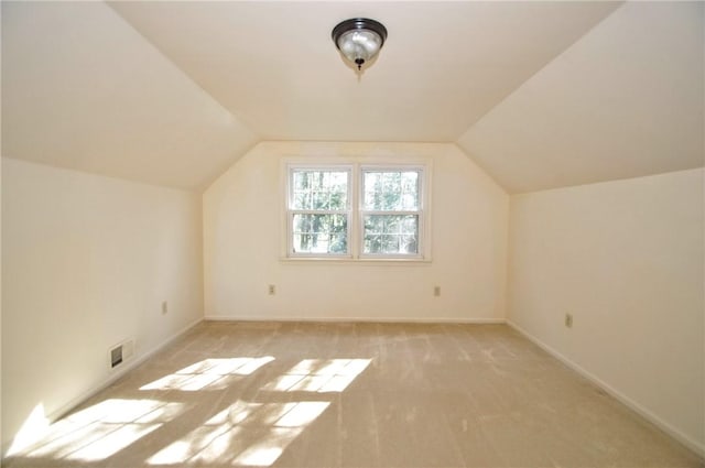 bonus room with baseboards, light carpet, vaulted ceiling, and visible vents