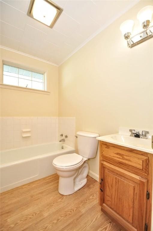 bathroom featuring crown molding, vanity, wood finished floors, toilet, and a bathtub