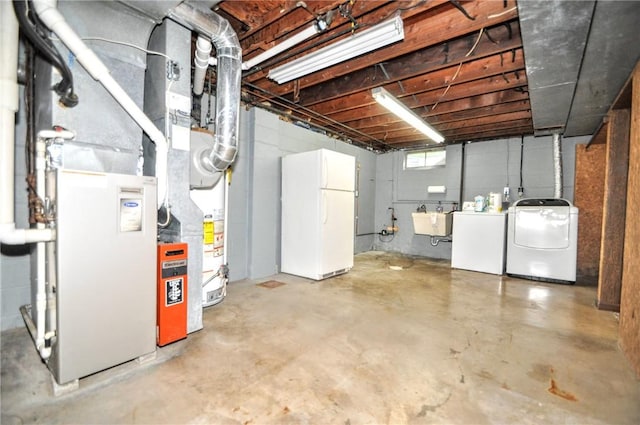basement featuring freestanding refrigerator, a sink, and washing machine and dryer