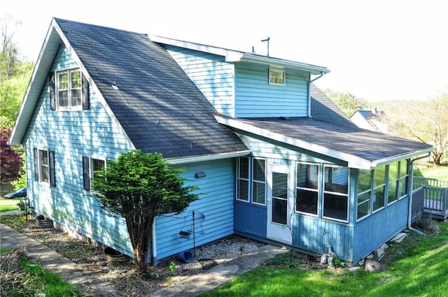 rear view of property with roof with shingles and a sunroom