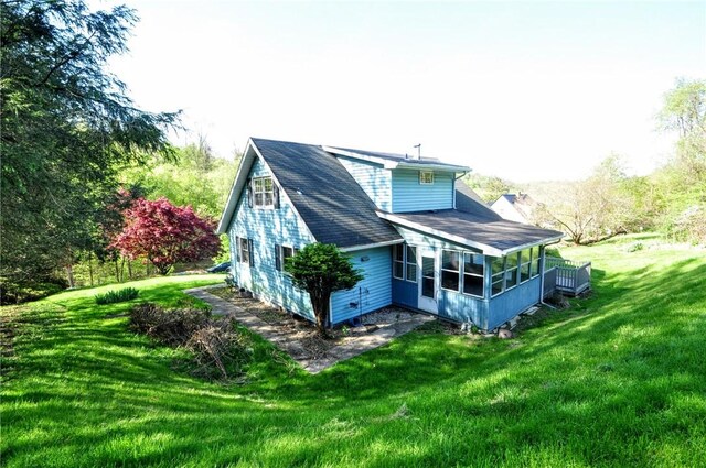 rear view of house with a sunroom and a yard