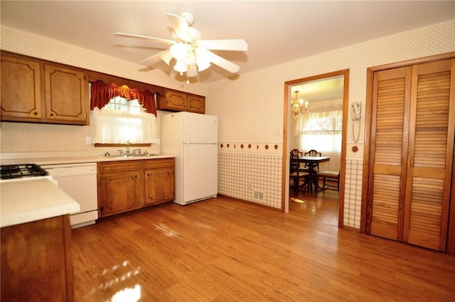 kitchen with a sink, light countertops, wallpapered walls, and white appliances