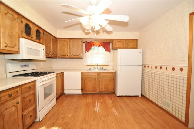 kitchen featuring visible vents, white appliances, ceiling fan, wallpapered walls, and a sink