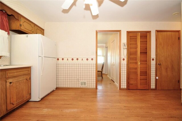 kitchen with light wood-style floors, freestanding refrigerator, a ceiling fan, wallpapered walls, and visible vents