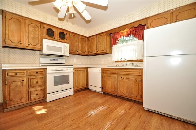 kitchen featuring white appliances, brown cabinets, a sink, and light countertops
