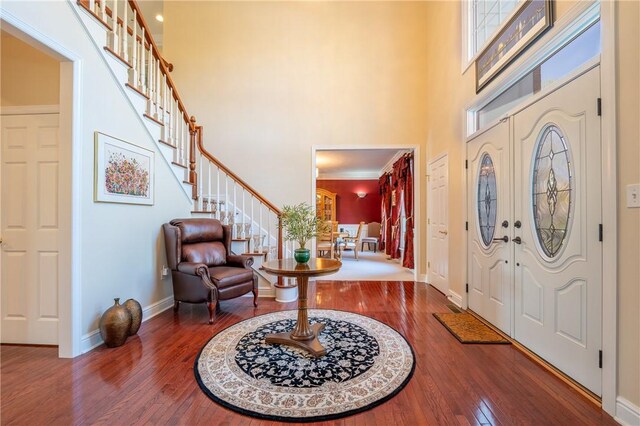 entrance foyer featuring wood-type flooring, a high ceiling, baseboards, and stairway