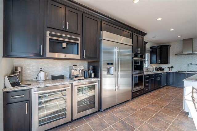 kitchen with wine cooler, appliances with stainless steel finishes, decorative backsplash, and wall chimney exhaust hood
