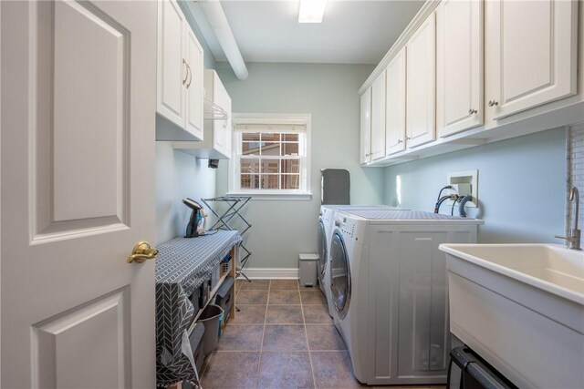 laundry room featuring cabinet space, a sink, separate washer and dryer, baseboards, and dark tile patterned floors