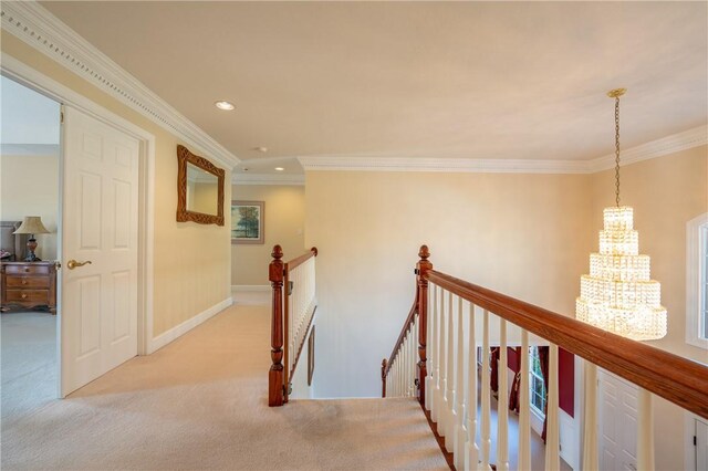 hallway featuring crown molding, light carpet, baseboards, a chandelier, and an upstairs landing